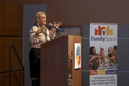 Woman speaking at podium, hands raised