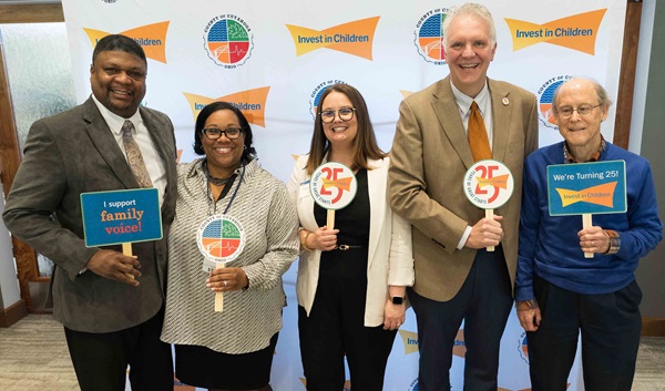 Group of people holding up signs celebrating 25 years of service
