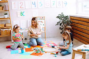 ChildCare Woman playing with children sitting on the floor.