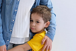 Sad little child, boy, hugging his mother at home, copy space.