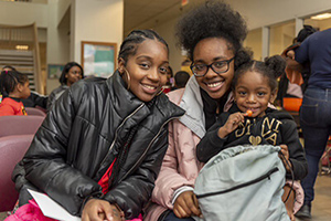 childfamilyfocused two young adults sitting and smiling with one holding a young child with a sucker