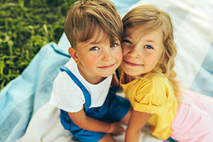 Outdoors close up portrait of smiling two children playing on the blanket outdoors.
