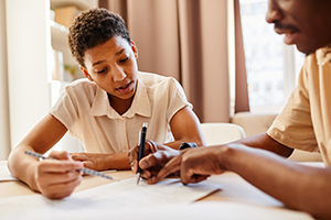 ChildTutor Warm toned portrait of teenage girl working with tutor and preparing for school exams.