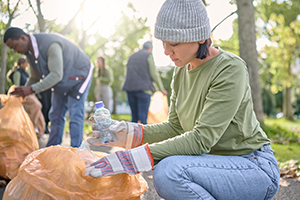 Trash, community volunteer and woman cleaning garbage pollution, waste product or team environment support.