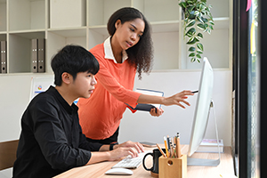 EmploymentTraining Woman training young man and pointing at something on a computer monitor.