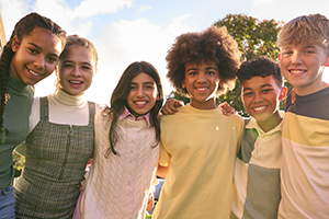 GroupChildren Group of children standing outside school building hugging.