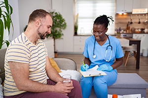 Friendly conversation between a nurse and a man during health assessment at home