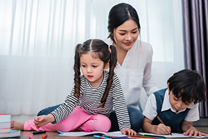 Woman with boy and girl who are coloring with colorful crayons at home.