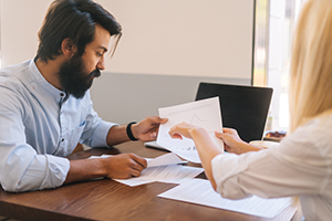 LegalAid Woman holding and pointing to a document to show a man something on the document.