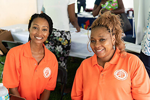 two women smiling and wearing orange shirts