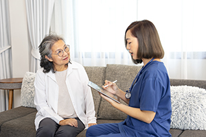 MedicarePremiumAssistance asian senior woman interested in a female nurse using digital tablet, giving advice self health care at home