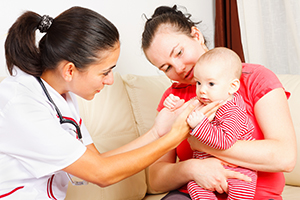 NewbornHomeVisit Baby boy held by his mother examined by pediatrician.