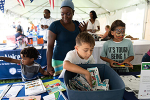 a woman with children doing crafts at a fair