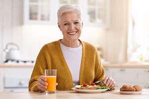 senior woman having a meal and juice at a kitchen table