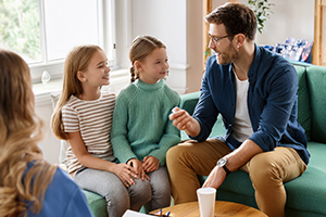 Two kids and an adult talk in a bright, modern space.