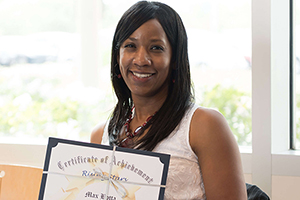 woman smiling and holding a certificate of achievement award