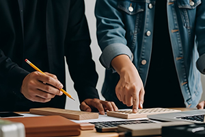 Two people working together on a project at a desk with laptops and papers.